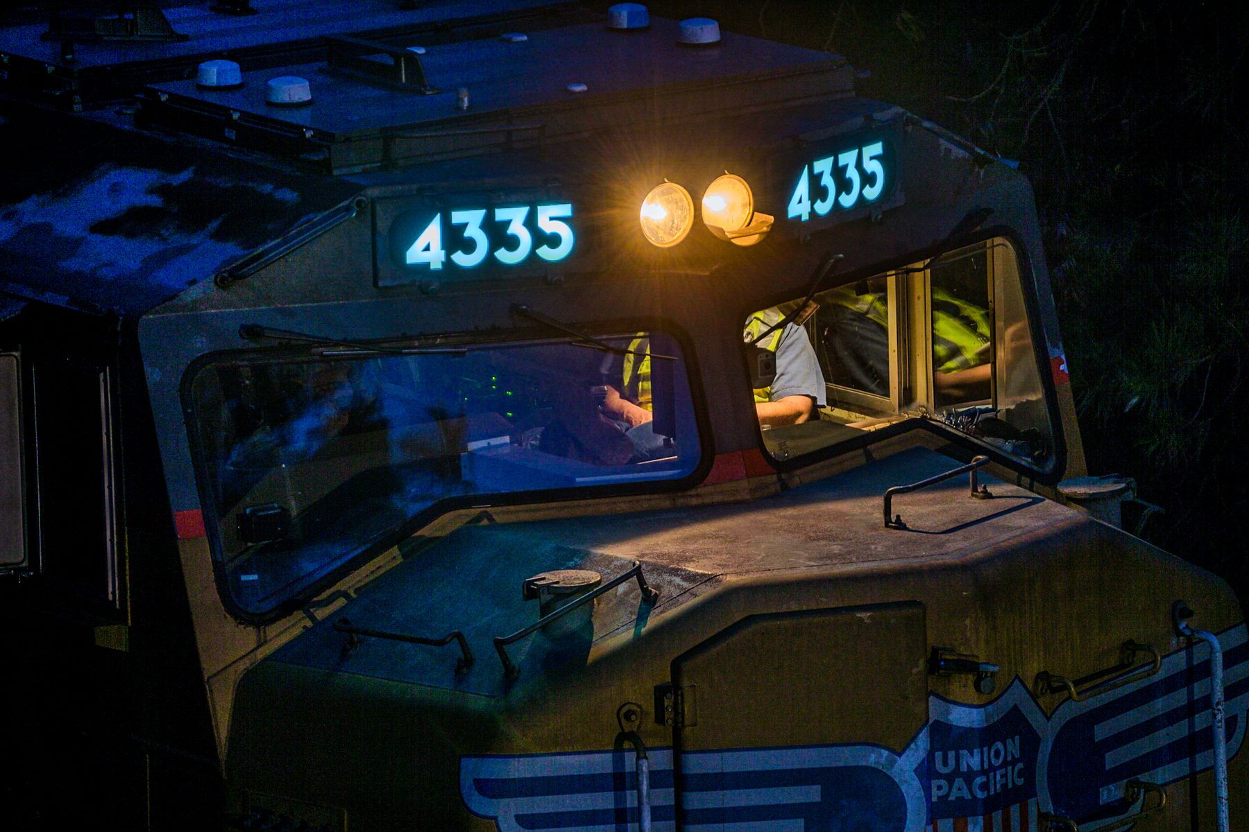Night photograph of a Union Pacific locomotive cab, number 4335, with the crew at the controls